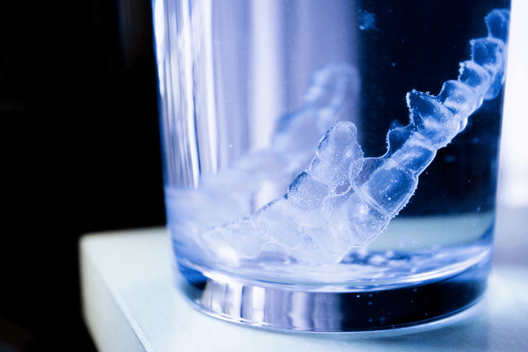clear aligners in cup of water blue closeup countertop